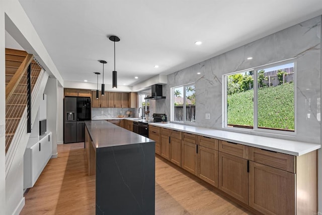 4687 Murat Ct, San Diego, CA 92117 - kitchen with black appliances, wall chimney exhaust hood, a center island, backsplash, and light wood-type flooring