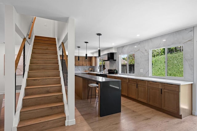4687 Murat Ct, San Diego, CA 92117 - kitchen featuring wall chimney exhaust hood, a kitchen breakfast bar, light wood-type flooring, brown cabinets, and recessed lighting