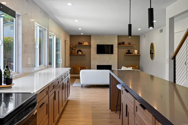 4687 Murat Ct, San Diego, CA 92117 - kitchen featuring light wood-type flooring, a tiled fireplace, pendant lighting, and recessed lighting