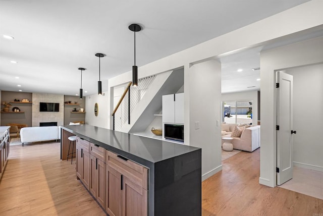4687 Murat Ct, San Diego, CA 92117 - kitchen with open floor plan, dark countertops, light wood finished floors, a fireplace, and pendant lighting