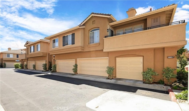5126 E Paddington Ct Unit F, Orange, CA 92867 - view of property featuring a chimney, stucco siding, and an attached garage