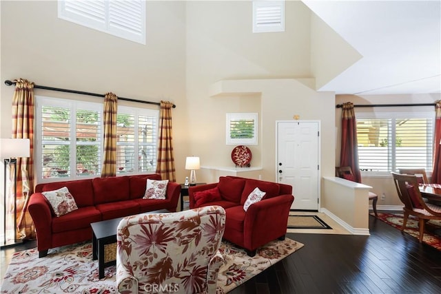 5126 E Paddington Ct Unit F, Orange, CA 92867 - living area with healthy amount of natural light, a towering ceiling, hardwood / wood-style flooring, and baseboards