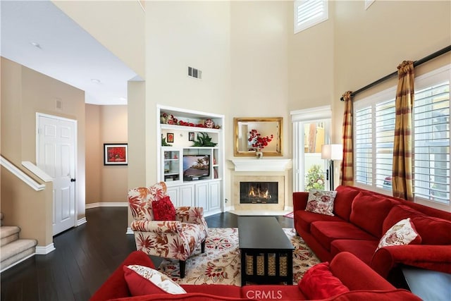 5126 E Paddington Ct Unit F, Orange, CA 92867 - living room featuring a towering ceiling, baseboards, dark wood-style flooring, a fireplace with flush hearth, and stairs