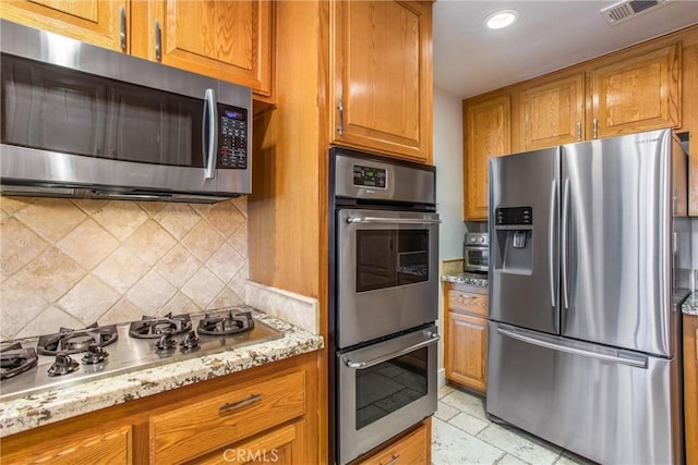 9914 Albany Ave, Rancho Cucamonga, CA 91701 - kitchen with stainless steel appliances, brown cabinets, decorative backsplash, light stone counters, and recessed lighting