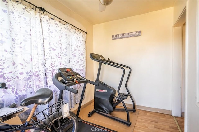 exercise area with wood finished floors and baseboards