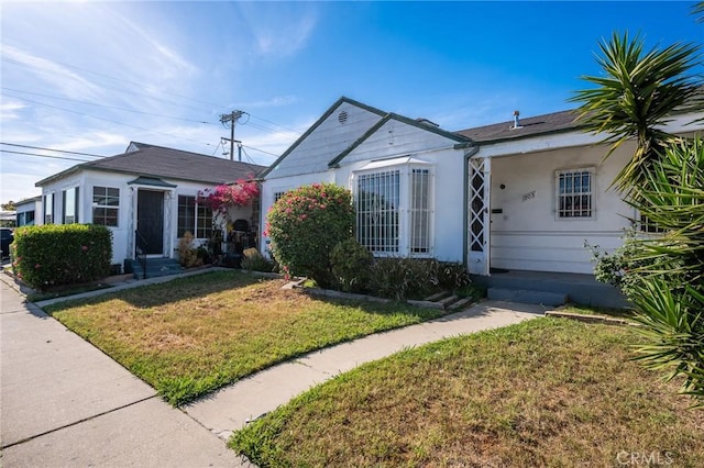 bungalow-style home with a front lawn and stucco siding