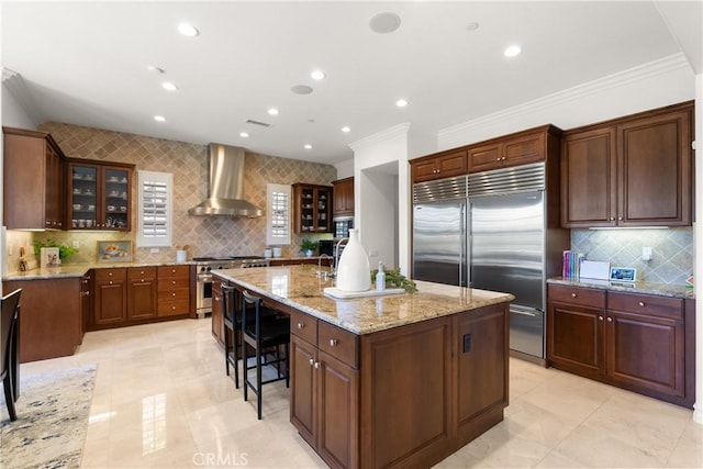 27371 Via Priorato, San Juan Capistrano, CA 92675 - kitchen featuring wall chimney range hood, high quality appliances, a center island with sink, backsplash, and light stone counters