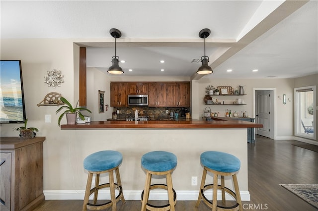 2731 N Rutgers Ave, Long Beach, CA 90815 - kitchen with stainless steel microwave, dark countertops, dark wood-type flooring, backsplash, and recessed lighting