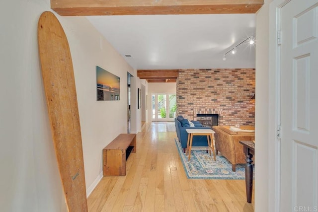 hall with beamed ceiling, light wood-type flooring, baseboards, and brick wall