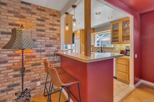 kitchen with a kitchen breakfast bar, light countertops, glass insert cabinets, and a sink