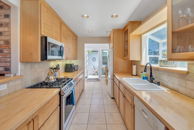 kitchen with stainless steel appliances, a sink, butcher block countertops, backsplash, and recessed lighting