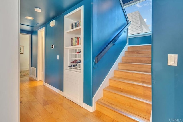 staircase featuring wood finished floors and baseboards