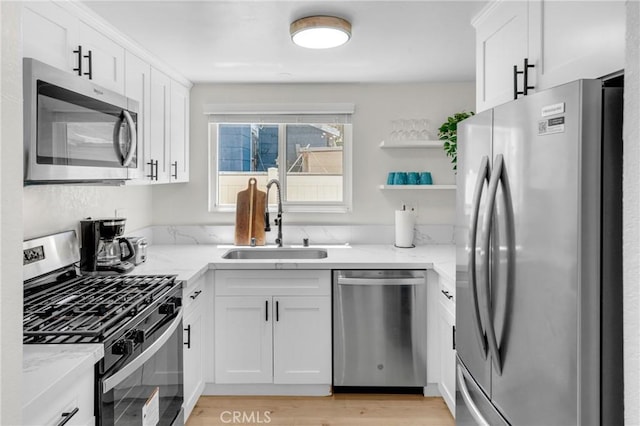 1075 Molino Ave Unit D, Long Beach, CA 90804 - kitchen featuring appliances with stainless steel finishes, a sink, open shelves, light stone countertops, and white cabinetry