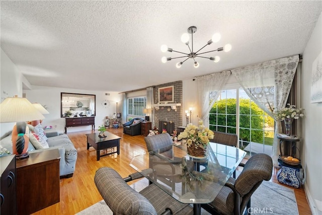2204 Ruiz Pl, Hacienda Heights, CA 91745 - dining space featuring a textured ceiling, a chandelier, light wood-style flooring, and a brick fireplace