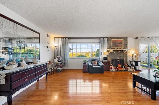 2204 Ruiz Pl, Hacienda Heights, CA 91745 - living room featuring a textured ceiling, light wood-style flooring, and a brick fireplace