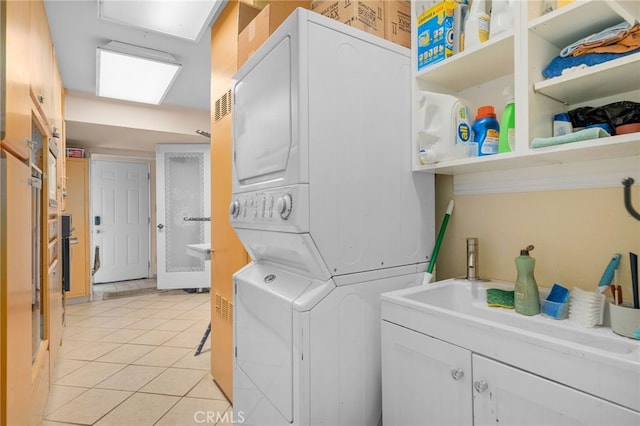 2137 N Murray St, Banning, CA 92220 - clothes washing area featuring stacked washer / dryer, light tile patterned flooring, and cabinet space