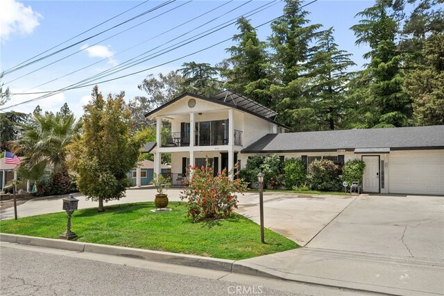 2137 N Murray St, Banning, CA 92220 - neoclassical / greek revival house featuring stucco siding, a balcony, a front yard, driveway, and a garage