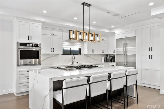 535 N Sierra Bonita Ave, Los Angeles, CA 90036 - kitchen featuring appliances with stainless steel finishes, a kitchen island, white cabinetry, dark wood-style flooring, and recessed lighting