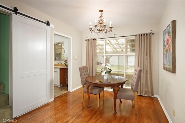 10345 Sherman Grove Ave, Sunland, CA 91040 - dining area featuring wood finished floors, a chandelier, a barn door, and baseboards