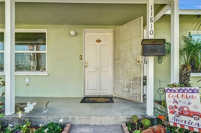 entrance to property with covered porch and stucco siding