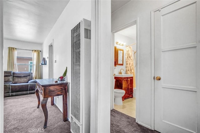 corridor with a heating unit, carpet flooring, and a sink
