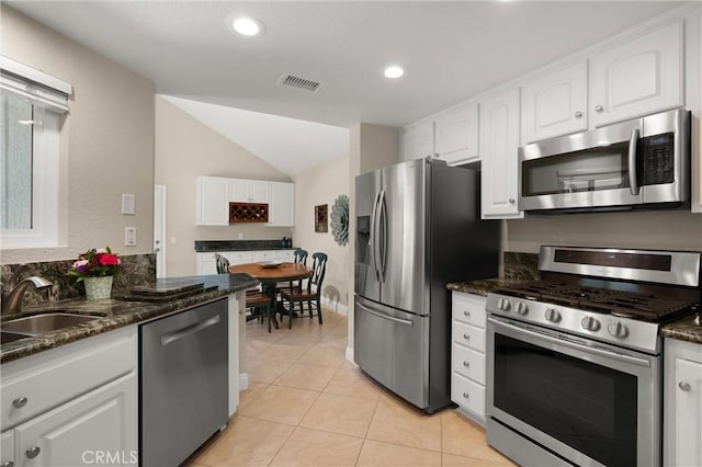 27345 Via Capri, San Juan Capistrano, CA 92675 - kitchen with appliances with stainless steel finishes, a sink, white cabinetry, vaulted ceiling, and dark stone counters