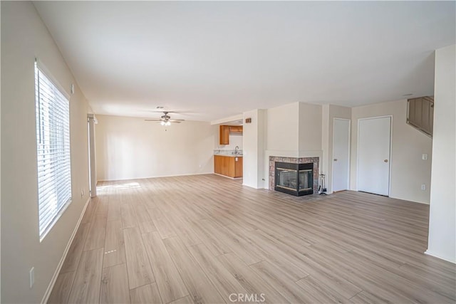 unfurnished living room with light wood-style flooring, a ceiling fan, and healthy amount of natural light