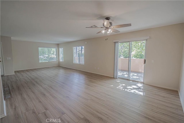 spare room with a ceiling fan, light wood-type flooring, and baseboards