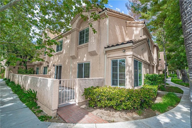 view of home's exterior featuring a fenced front yard, stucco siding, and a tile roof