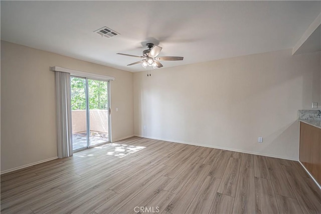 spare room featuring ceiling fan, light wood-style floors, and baseboards