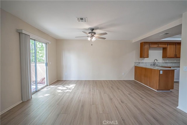 unfurnished living room with light wood finished floors, a ceiling fan, baseboards, and a sink