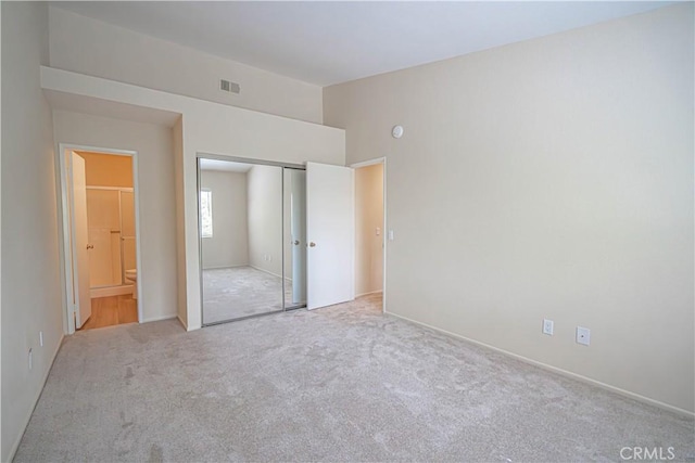 unfurnished bedroom featuring carpet floors, a closet, and ensuite bath