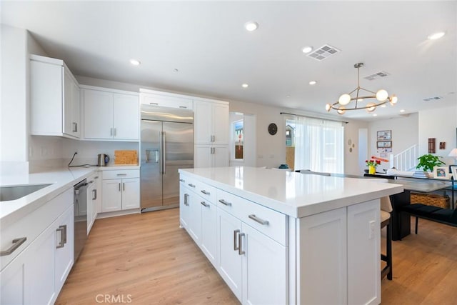 188 Merit, Irvine, CA 92618 - kitchen with appliances with stainless steel finishes, white cabinets, a center island, light countertops, and light wood finished floors