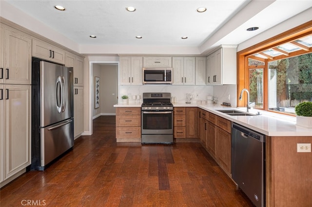 kitchen featuring appliances with stainless steel finishes, a sink, dark wood-type flooring, light countertops, and recessed lighting