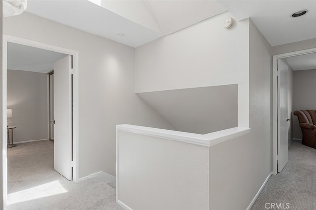 hall with carpet floors, an upstairs landing, and baseboards