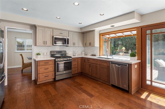 kitchen featuring appliances with stainless steel finishes, a sink, dark wood finished floors, light countertops, and recessed lighting