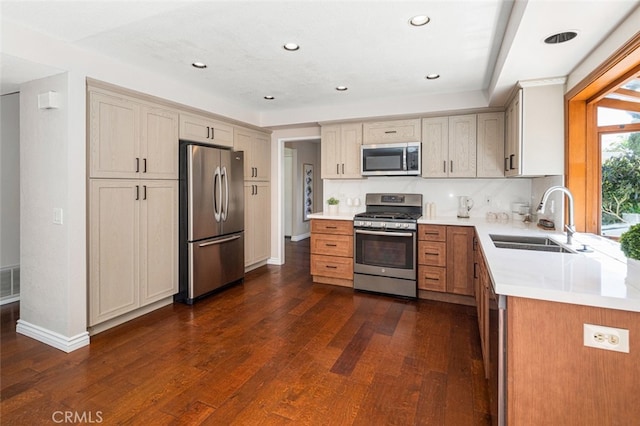 kitchen featuring appliances with stainless steel finishes, a sink, dark wood-style flooring, light countertops, and baseboards