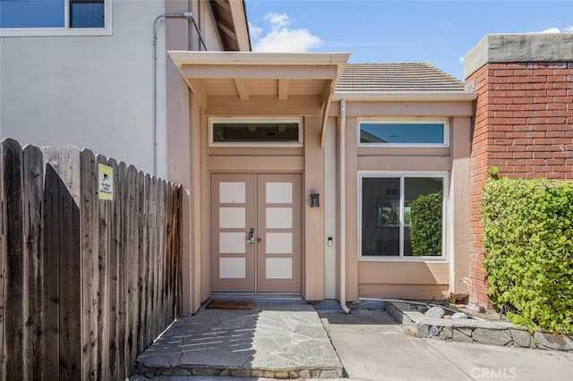 entrance to property featuring stucco siding and fence