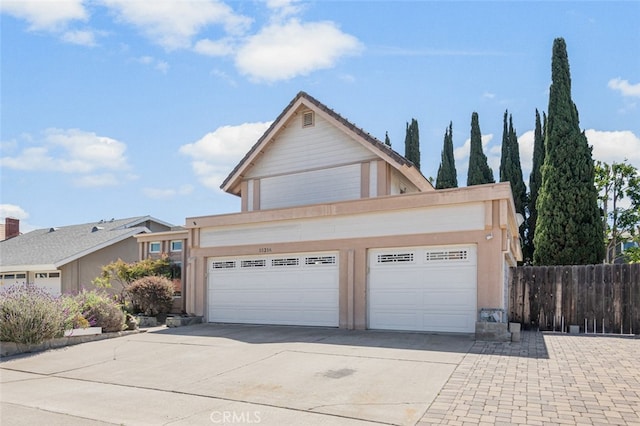 view of front of home featuring driveway, fence, and a garage