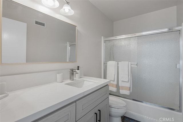 full bath featuring vanity, toilet, and combined bath / shower with glass door