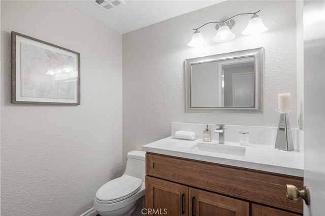 bathroom with toilet, a textured wall, and vanity