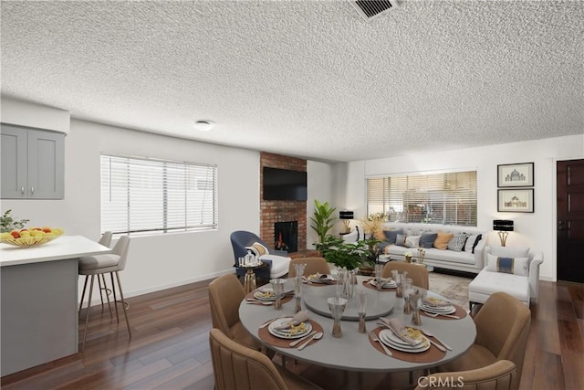 dining space with a textured ceiling, dark wood-type flooring, a fireplace, and baseboards