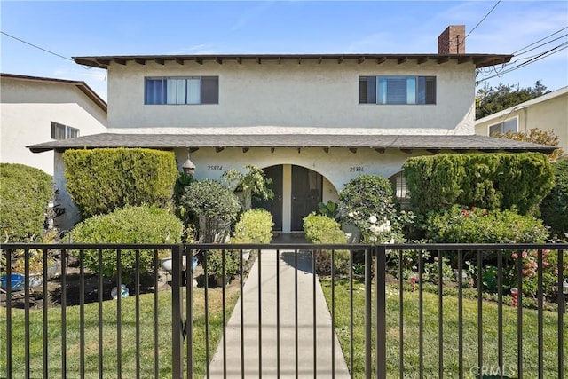 view of front facade with stucco siding, a chimney, and a front yard
