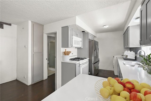 kitchen with white appliances, gray cabinetry, a sink, light countertops, and a textured ceiling