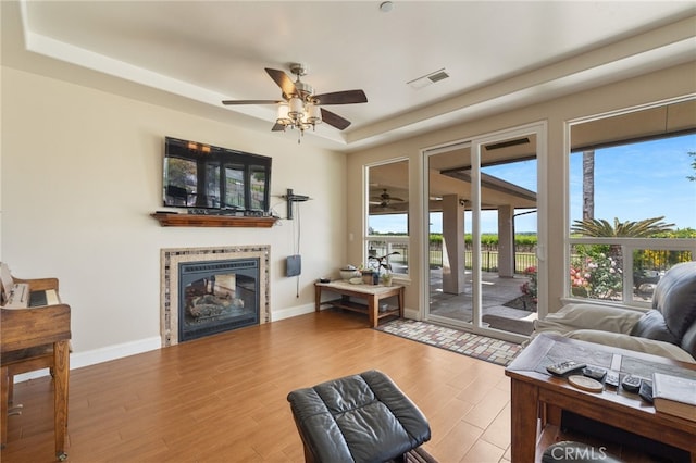 38792 Comanche Point Rd, Arvin, CA 93203 - living room with a ceiling fan, a fireplace, wood finished floors, a tray ceiling, and baseboards