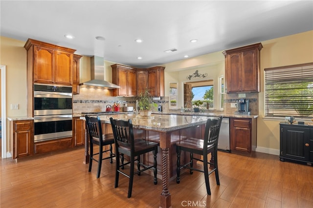 38792 Comanche Point Rd, Arvin, CA 93203 - kitchen with stainless steel appliances, wall chimney range hood, a kitchen bar, decorative backsplash, and recessed lighting