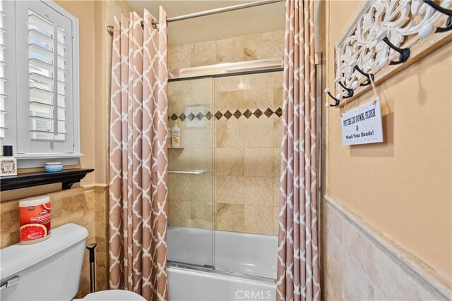 28456 Calex Dr, Valencia, CA 91354 - bathroom with tile walls, bath / shower combo with glass door, toilet, and a wainscoted wall