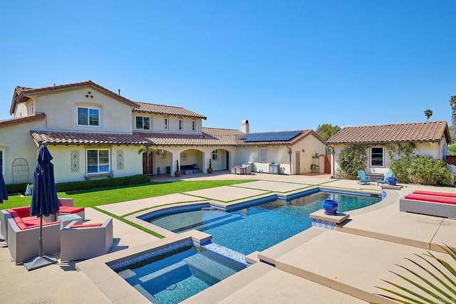 rear view of property featuring stucco siding, a patio area, roof mounted solar panels, a tiled roof, and a pool with connected hot tub