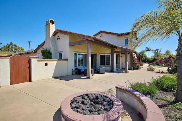 back of property with a gate, a chimney, stucco siding, a patio, and a tile roof