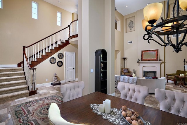 dining room featuring a high ceiling, stairway, a fireplace, and baseboards
